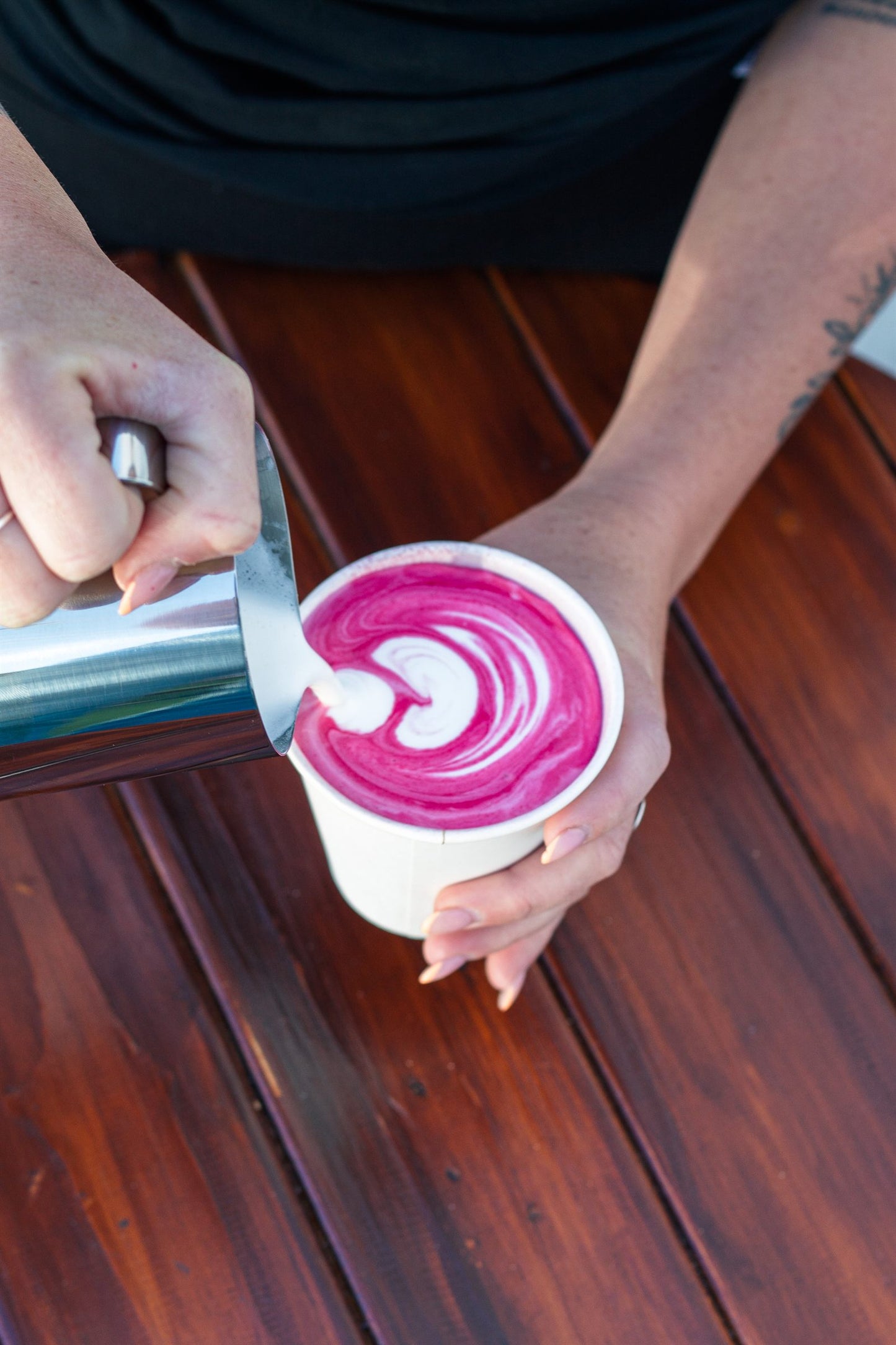 Milk pouring into a vivid pink beetroot latte