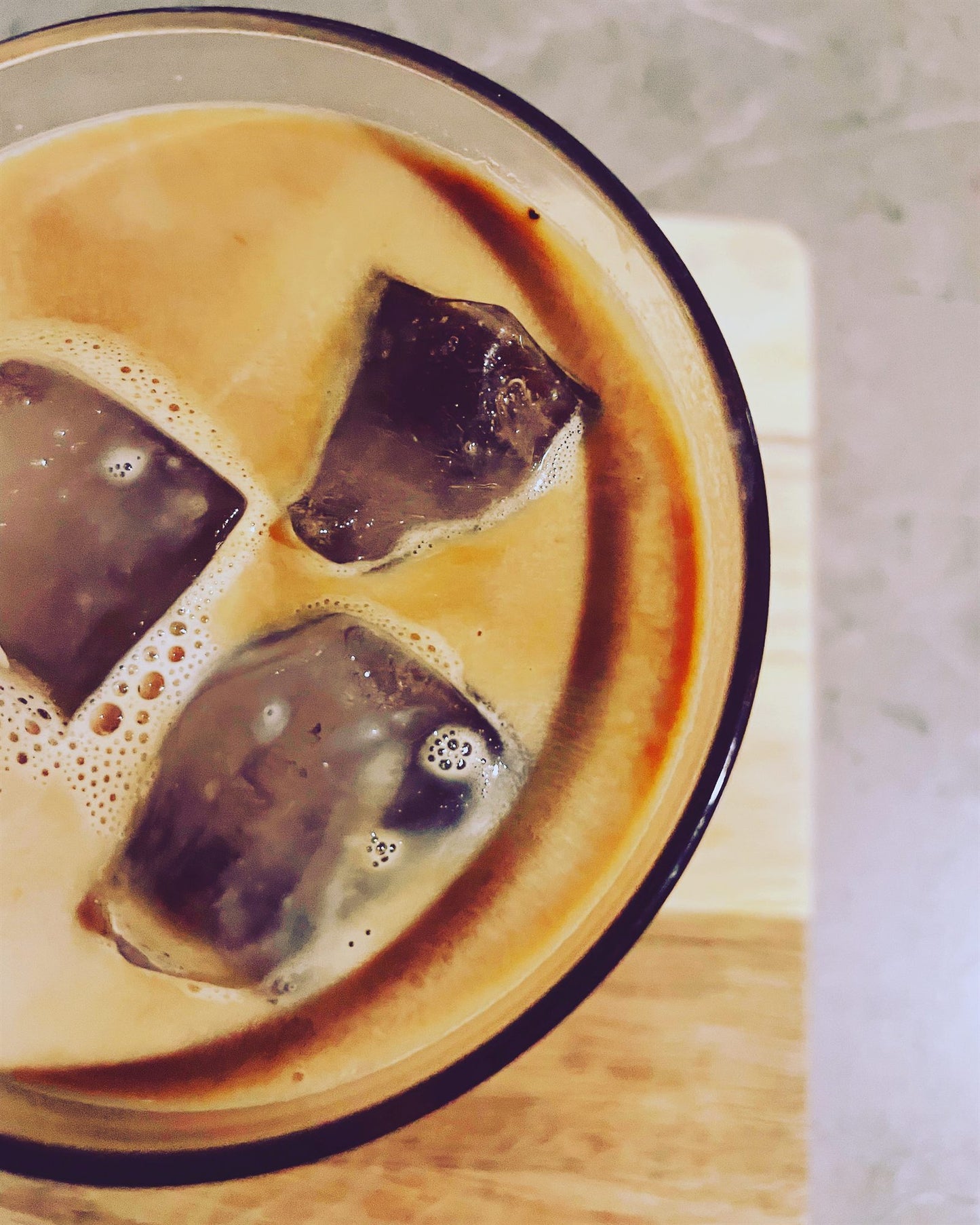 Iced coffee swirling with cream, overhead close up