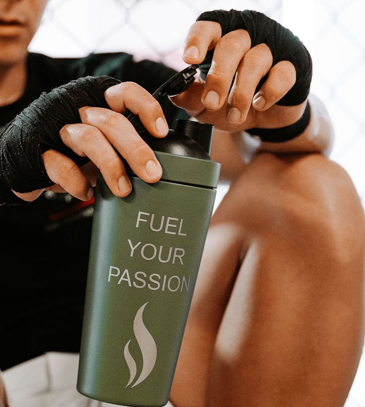 Athlete with hand wraps opening a Brewdy shaker at the gym